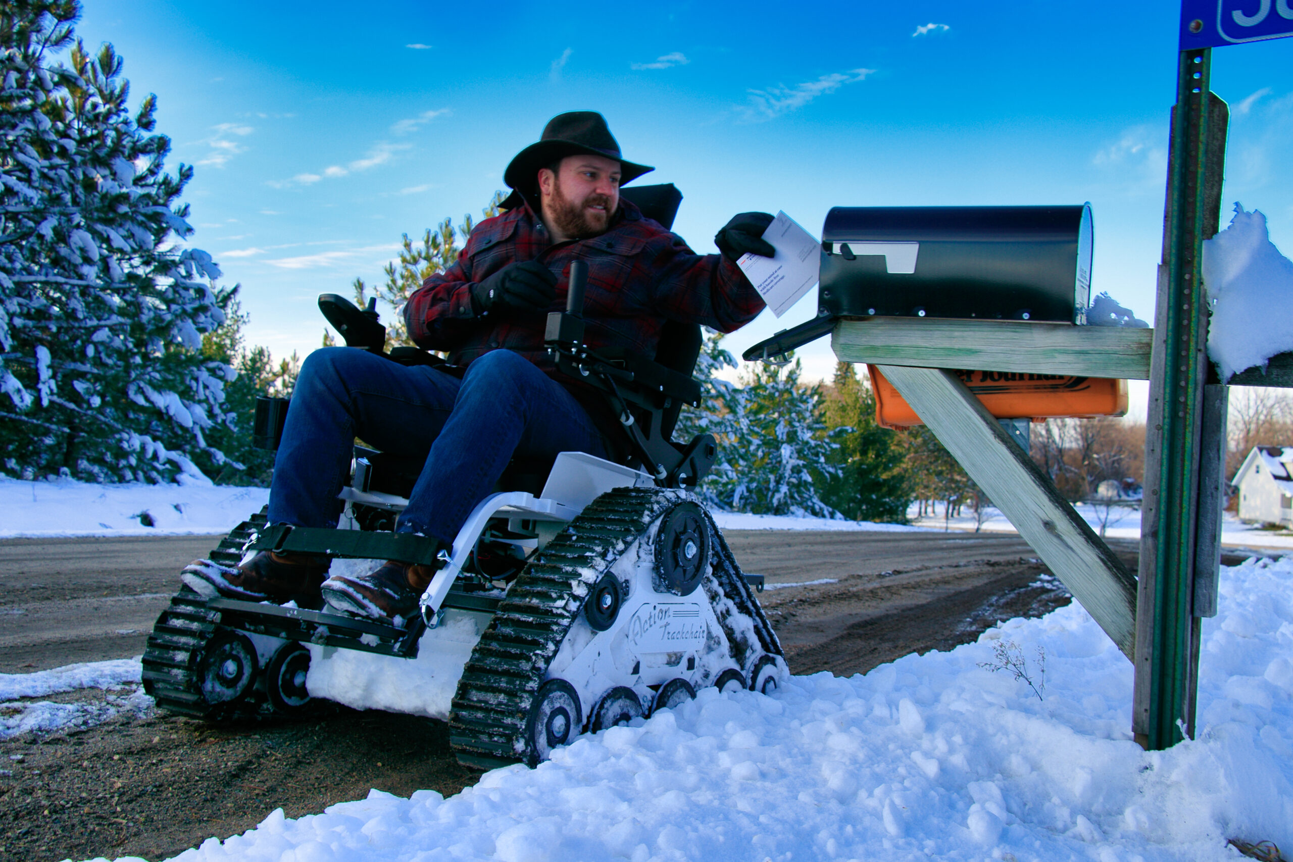 Persona en silla de ruedas todoterreno modelo STS en la nieve recogiendo el correo